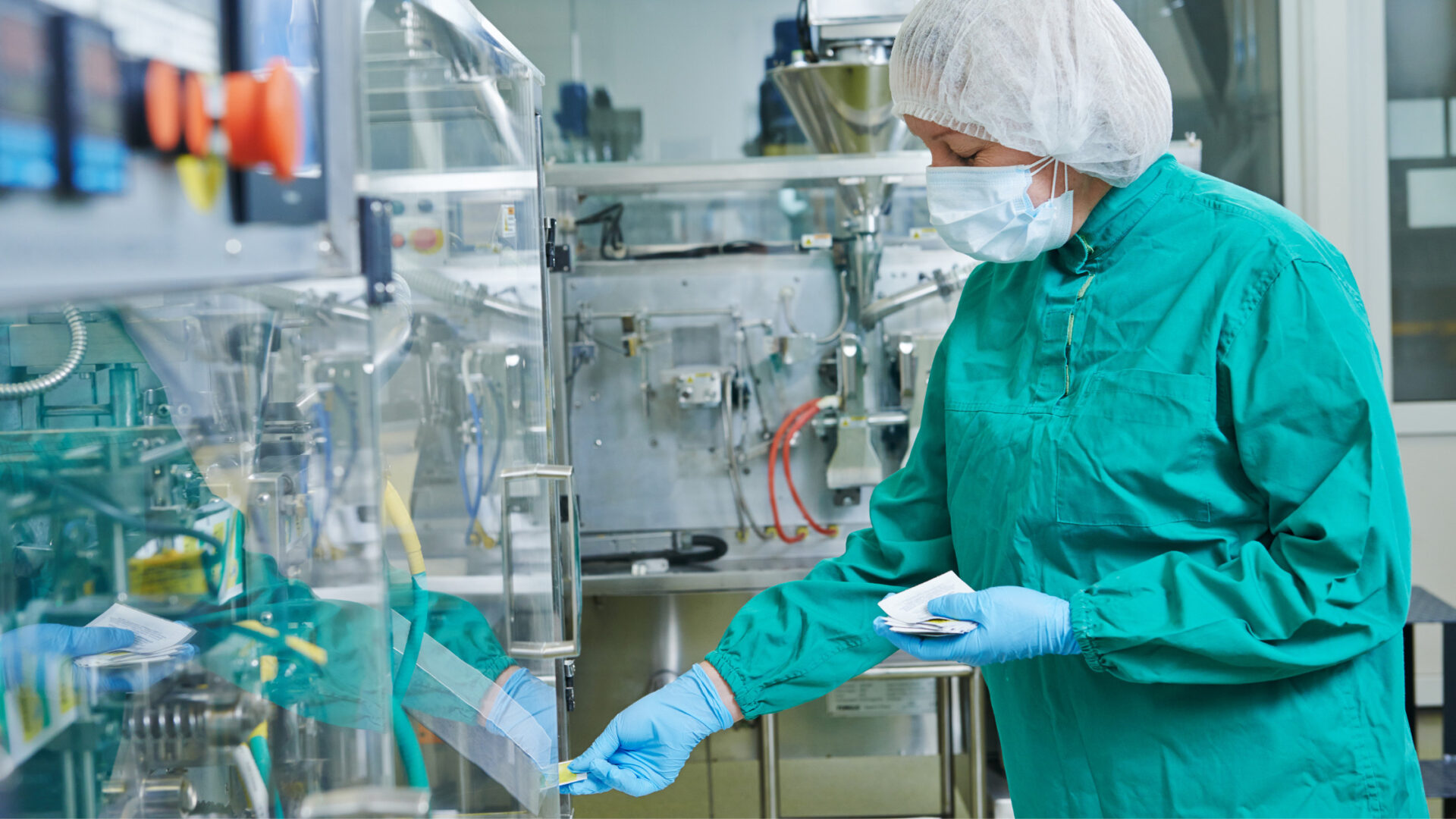 Profesional de laboratorio con vestimenta de bioseguridad controlando el proceso de envasado en una máquina automatizada, un ejemplo de las mejoras en trazabilidad de medicamentos que se pueden lograr implementando el kit 4.0 farmacéutica.
